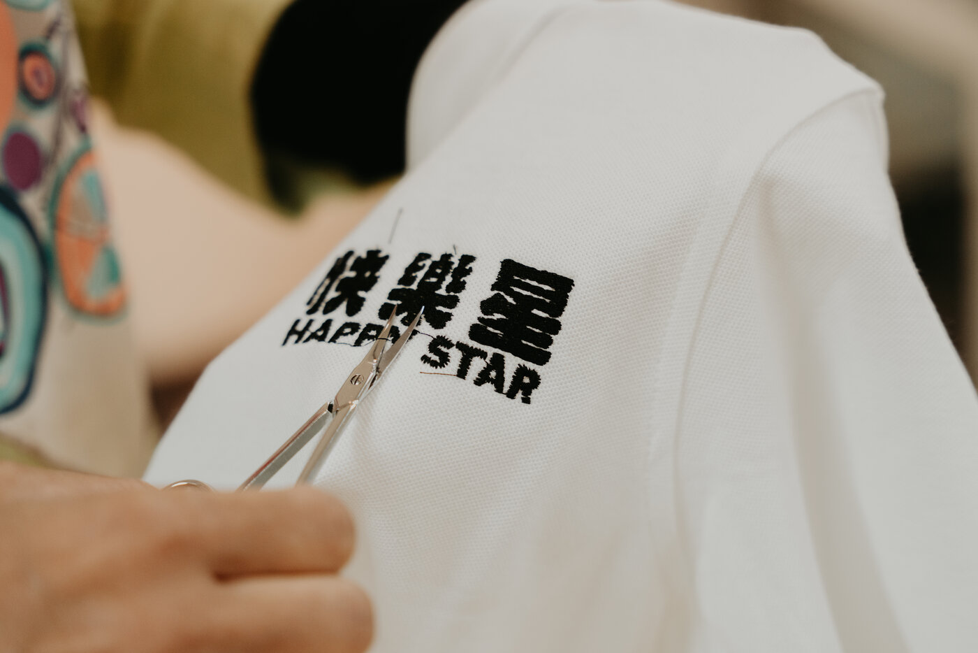 Trimming jump stitches on a freshly embroidered Happy Star polo