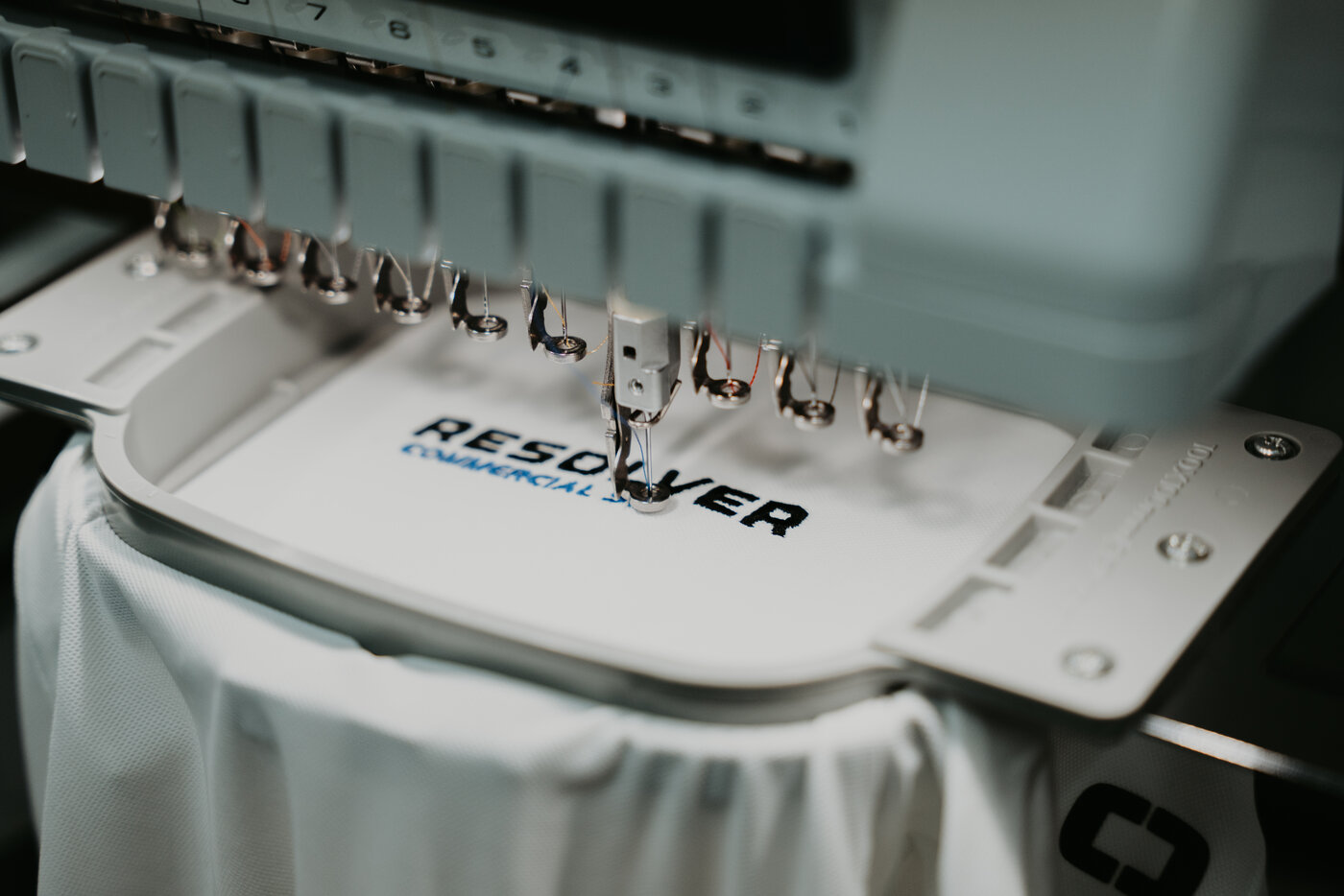 Close-up of an embroidery machine needle bank stitching a logo