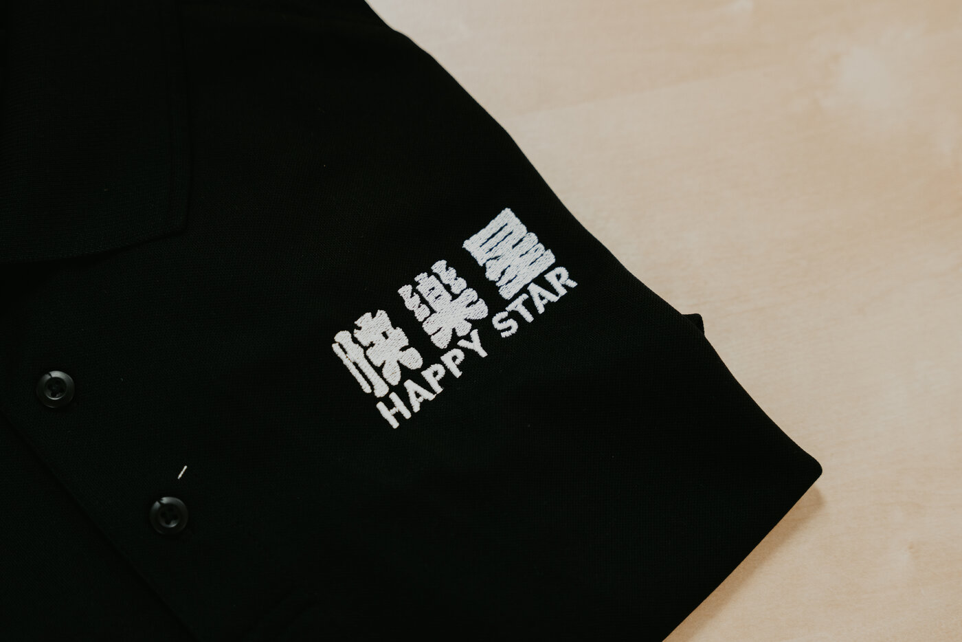 Embroidered Happy Star logo on a custom black polo, produced in-house