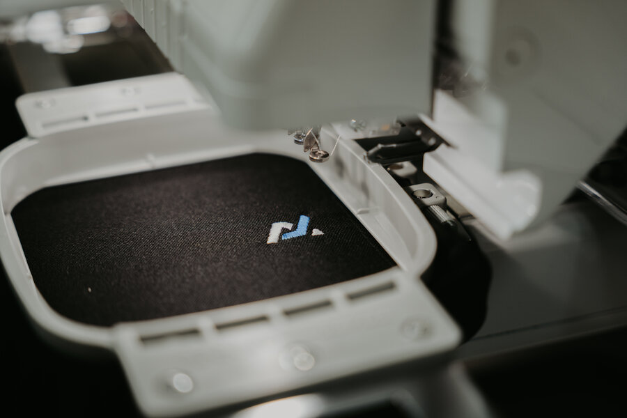 Close-up of a small embroidered logo on black fabric
